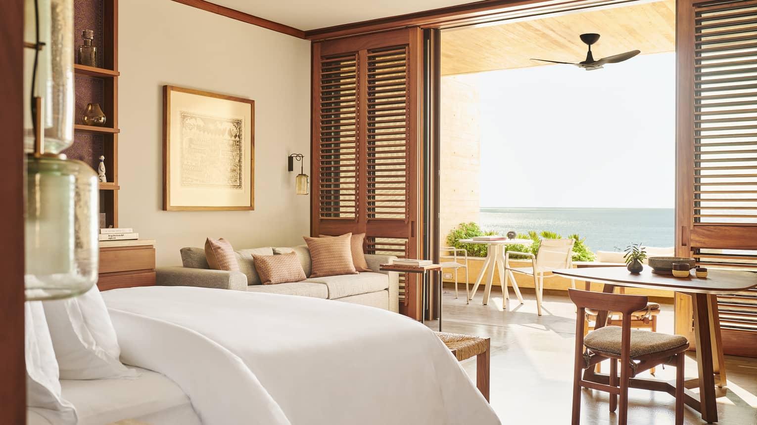 Beach-view hotel room with shutter doors opening to terrace