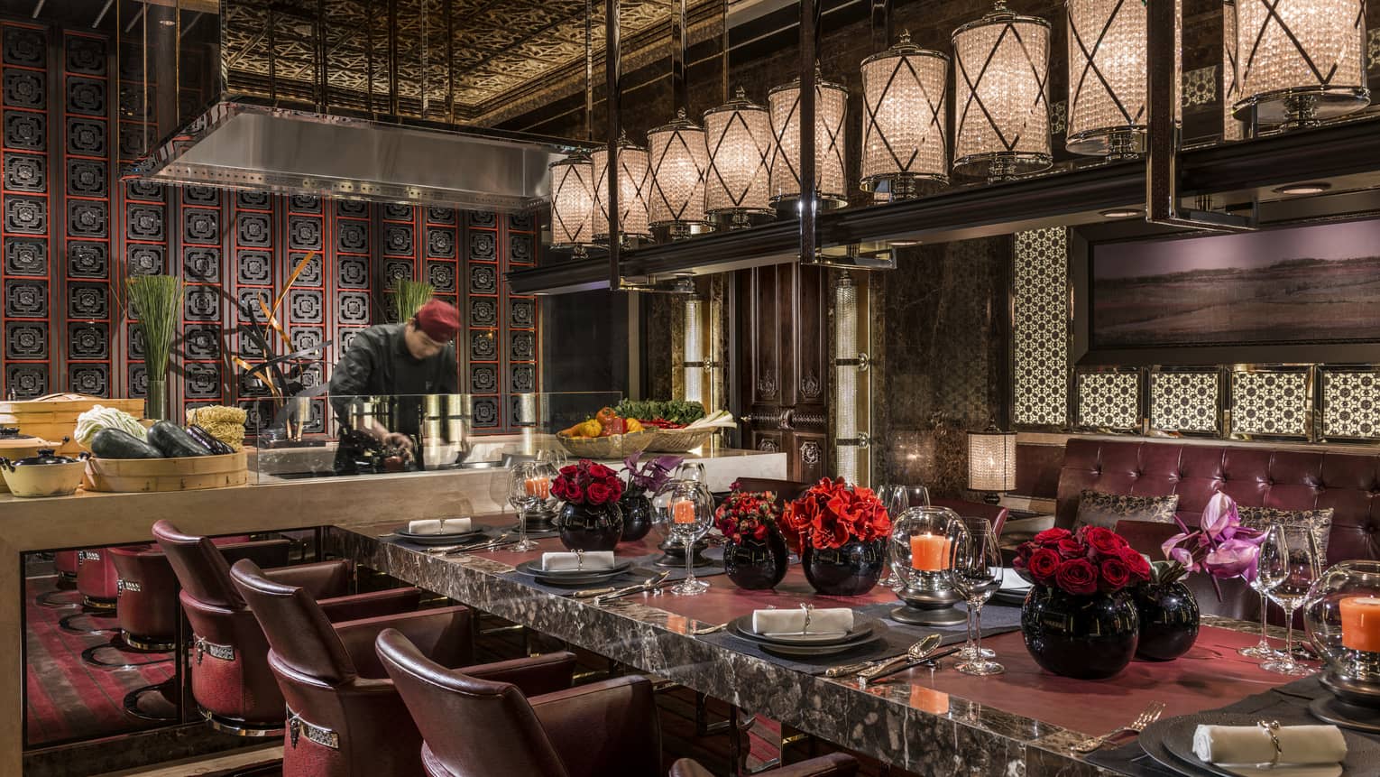 Elegant eight-person black marble Chef's Table in front of chef at open kitchen line, row of lanterns above