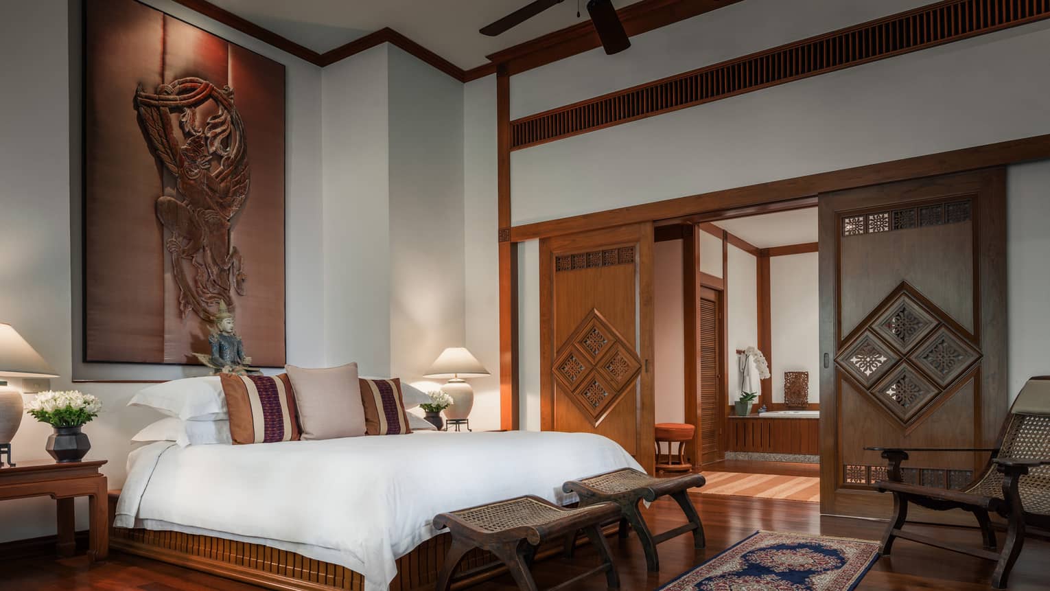 Penthouse Residence bedroom with high ceilings, wood sculpture over bed, sliding wood doors 