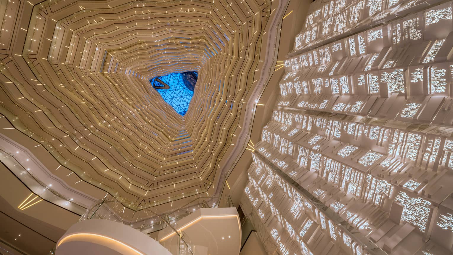 Triangular skylight seen past many floors of curved white balconies inside Four Seasons Hotel Guangzhou