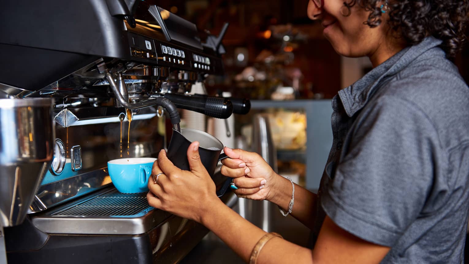 Smiling barista makes Big Island Coffee Roasters coffee at espresso machine
