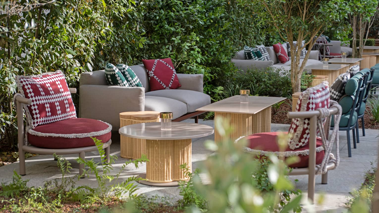 Stilla Garden restaurant patio with wooden tables, red chairs, tan couches with red and green pillows