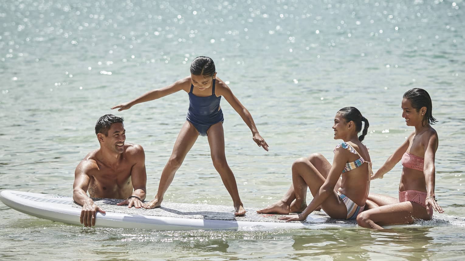 A family sitting on a large surf or paddleboard.