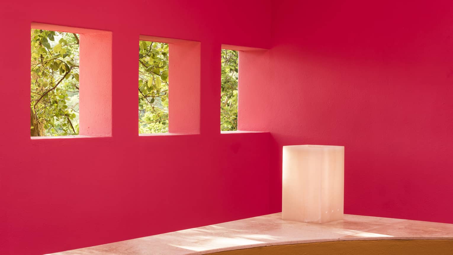 Pink walls with three cut-out windows looking out to trees