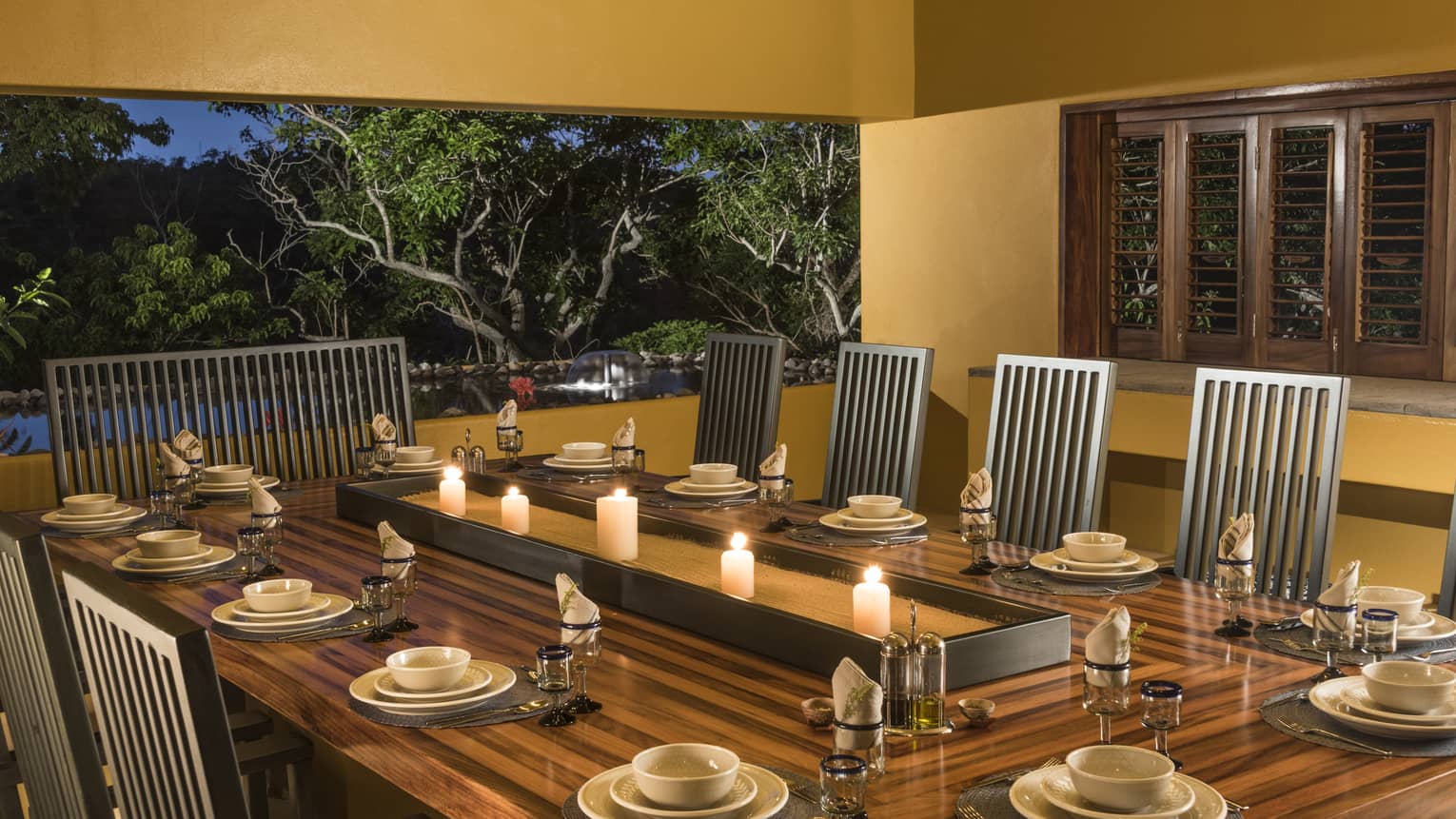 Dining table with 10 seats, set for dinner, opening to a terrace