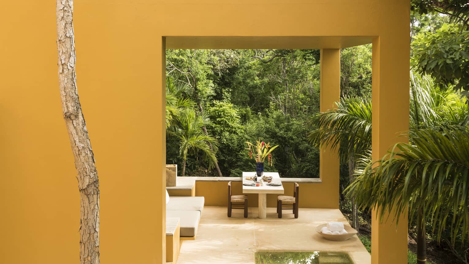 Covered terrace of stucco villa, surrounded by jungle forest