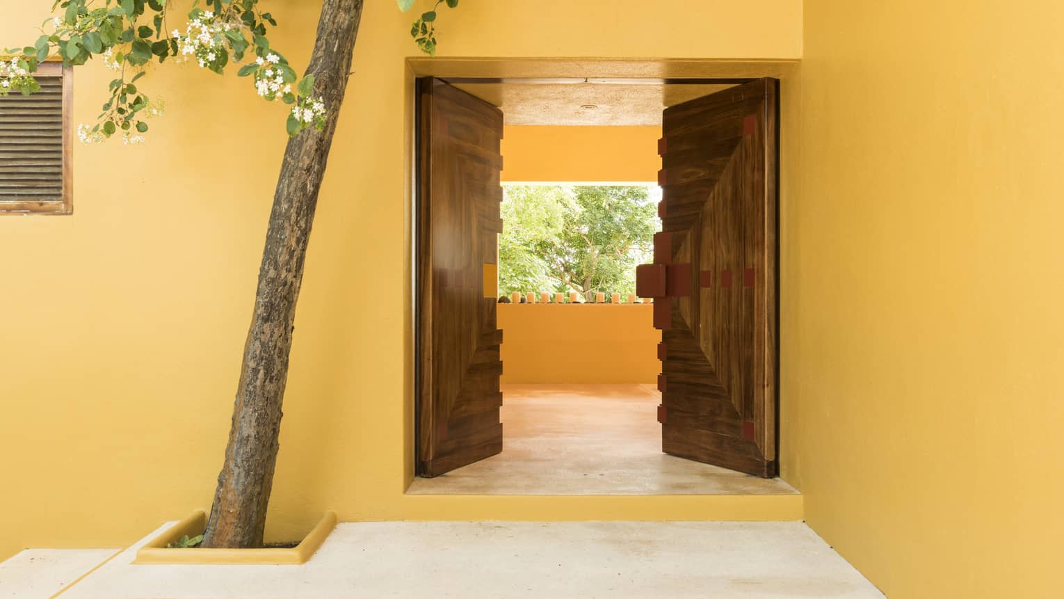 Two wooden doors, entryway into a yellow-walled villa