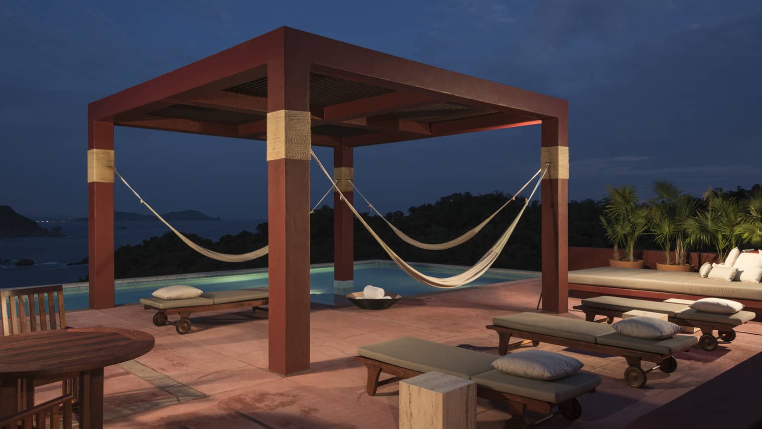 Pool terrace with red wood pergola at night
