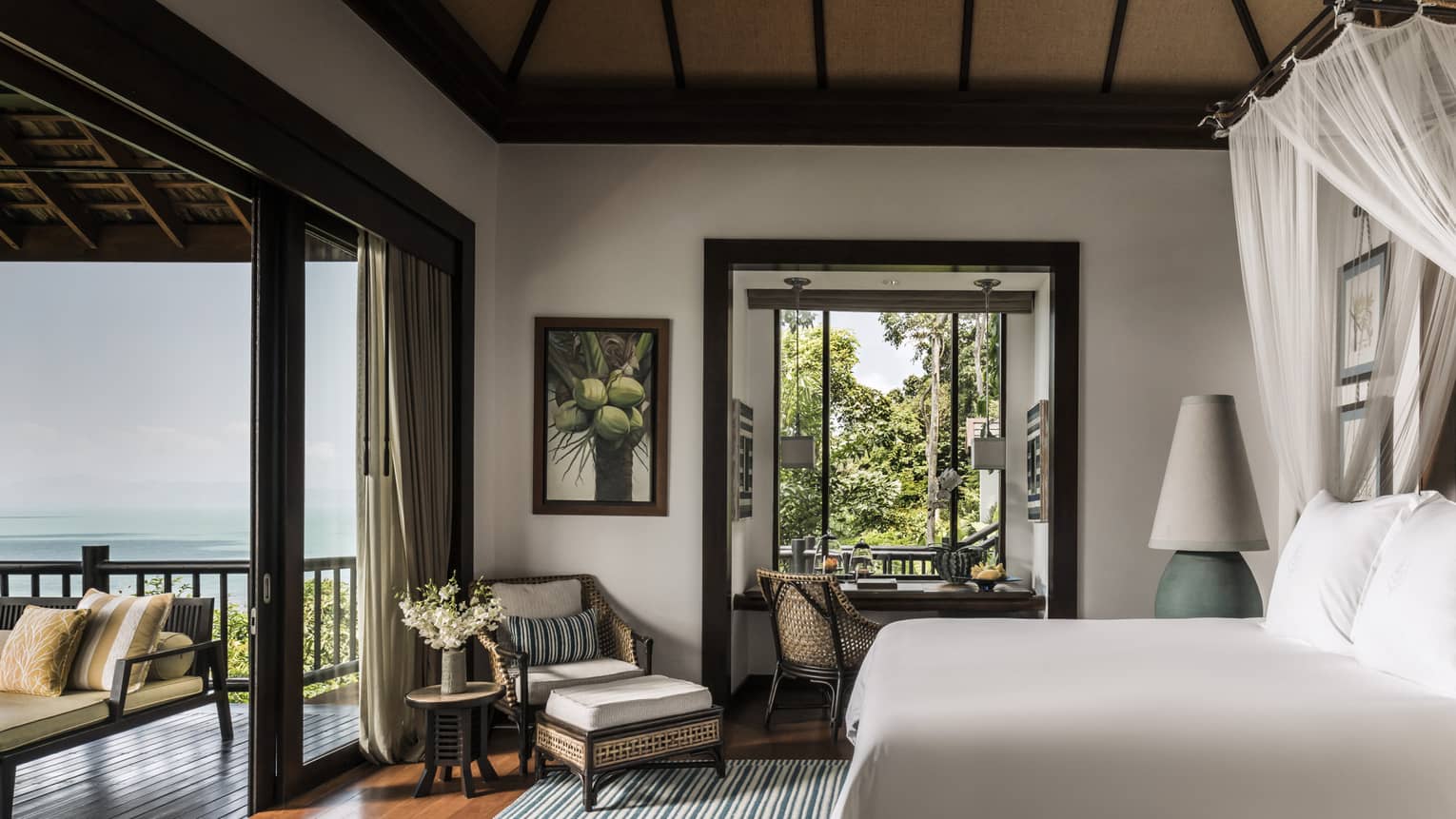 Deluxe One-Bedroom Pool Villa bedroom with bed, wicker armchair, open-air wall to patio