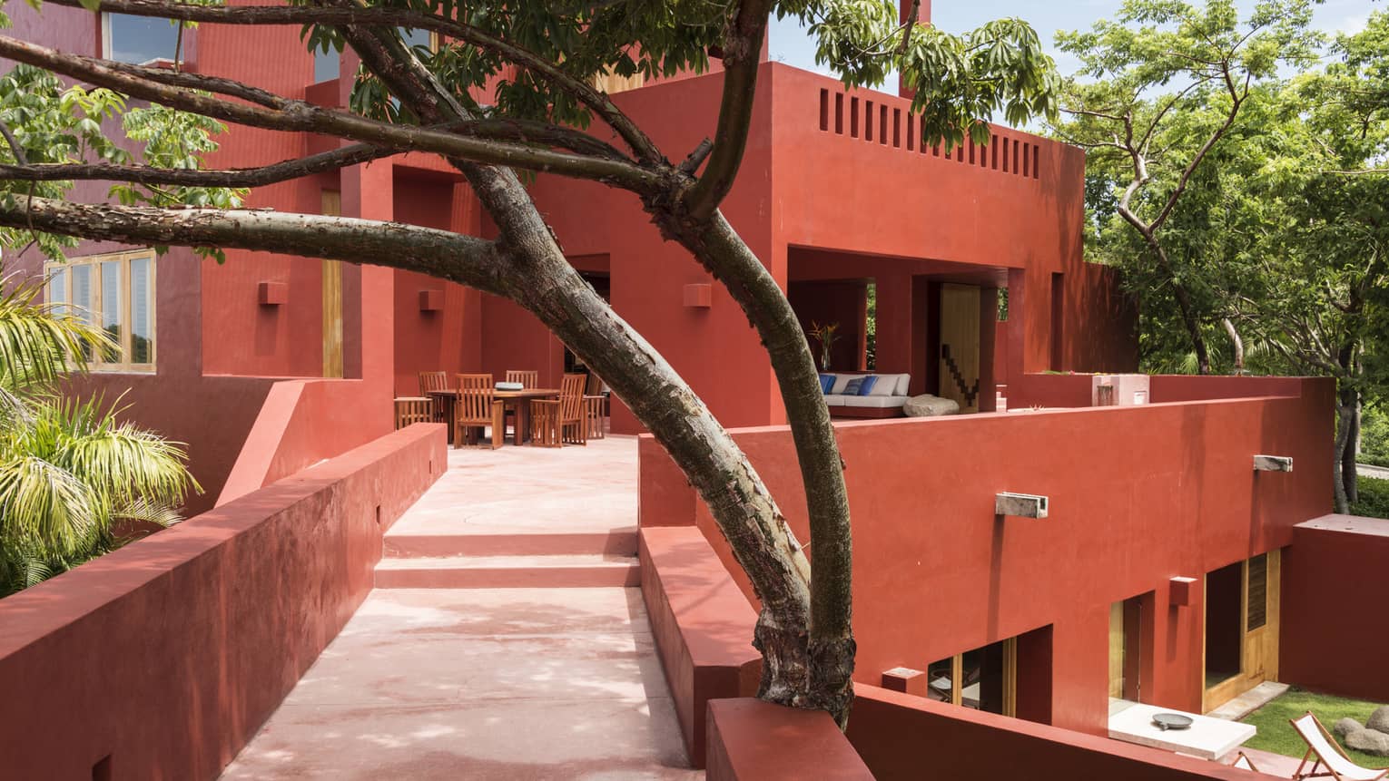 Red villa entrance walkway, surrounded by trees