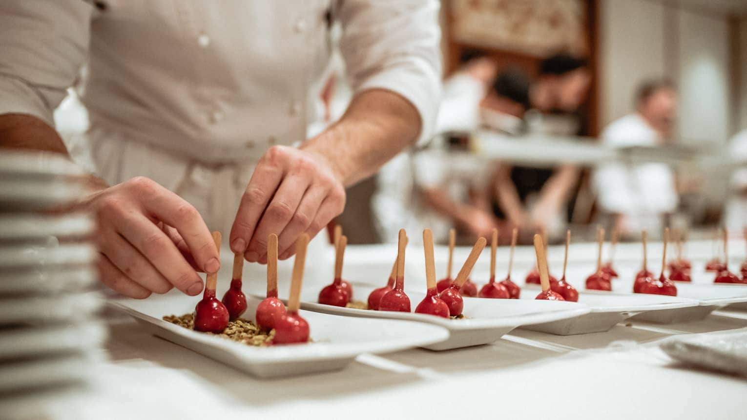 A pastry chef making a dessert of red berries in a brown dust.