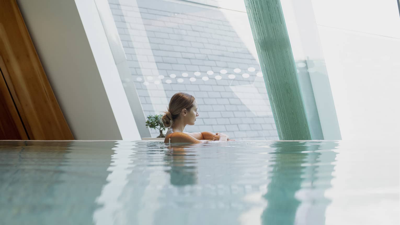 Woman in infinity-edge pool looking out window