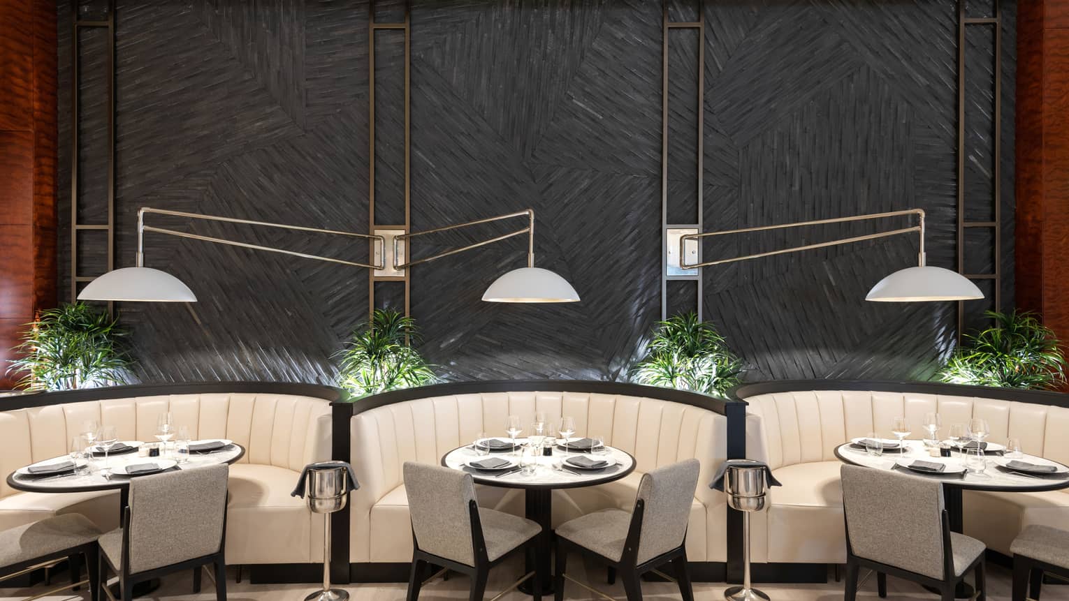 Three round dining tables next to each other surrounded by a curved booth and two chairs each.