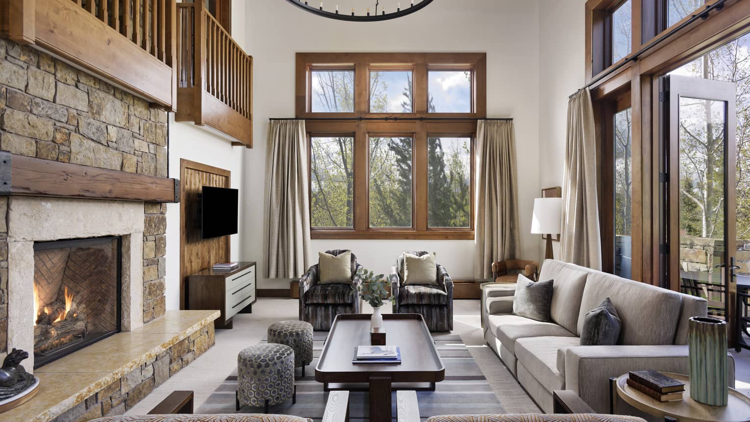 Living room with sofa and four arm chairs, stone fire place, open loft