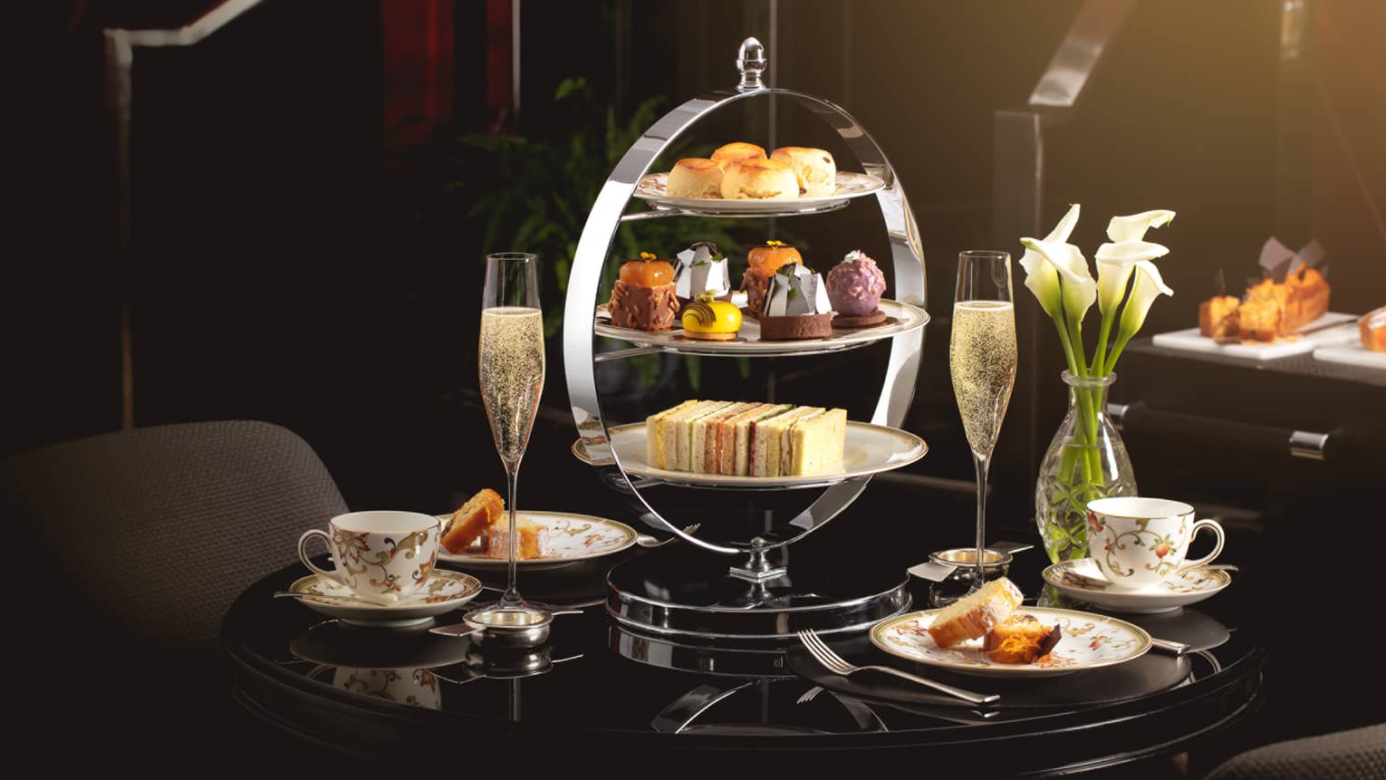 Afternoon tea tray with sweets, tea cups and Champagne on table