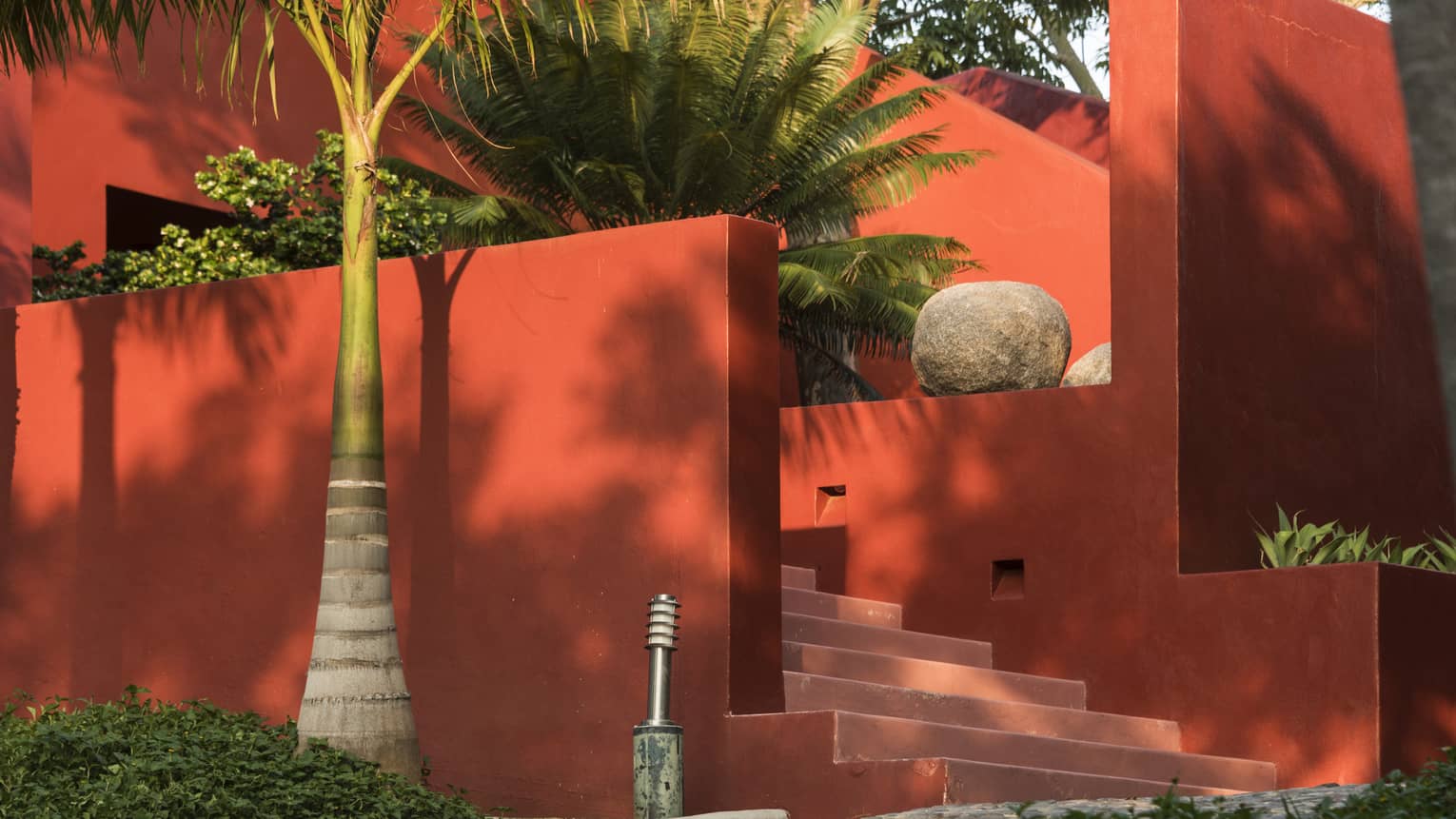 Exterior of red stucco villa with palm trees