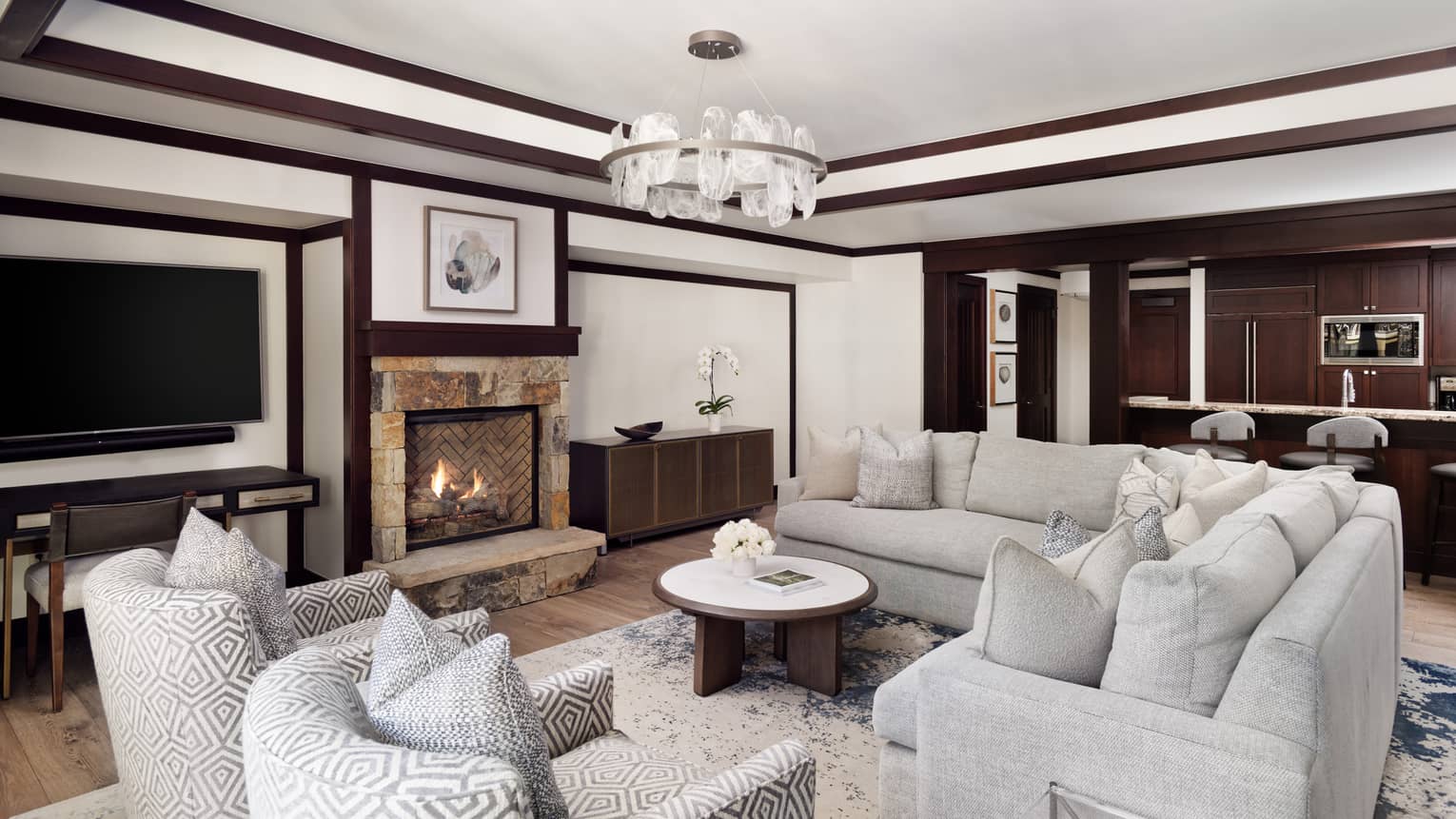 Living room with light grey sectional sofa, two arm chairs and stone fireplace