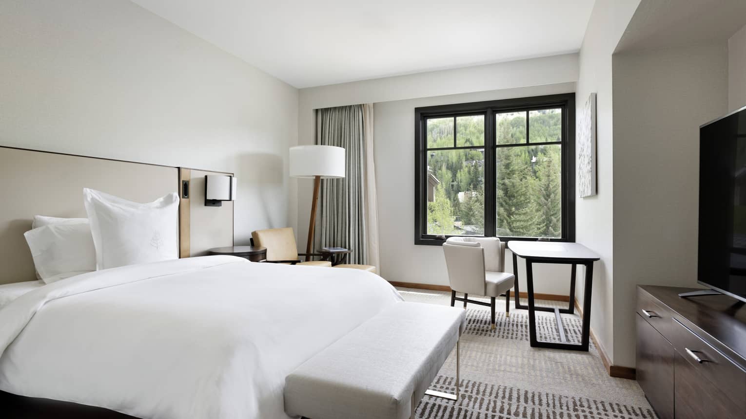 Luxury resort residence bedroom with king bed, arm chair, desk and window