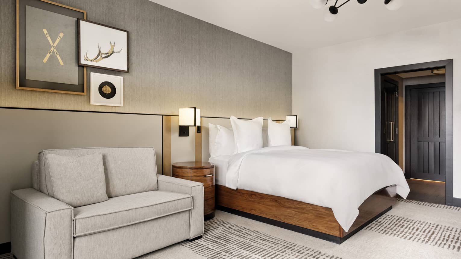 Contemporary bedroom featuring a king bed with wooden base and white sheets, plus a small sofa