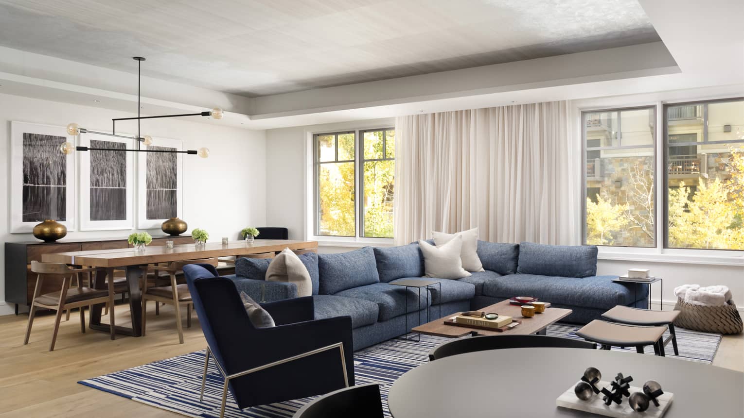 Living room with blue sectional sofa, blue velvet armchair, dining table