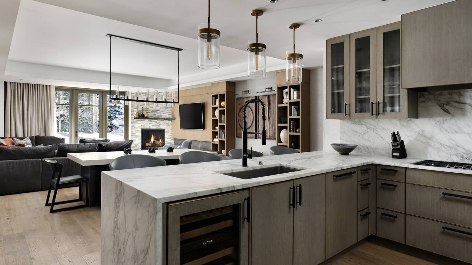 Kitchen with marble counters, wine fridge, grey cupboards, three glass lights