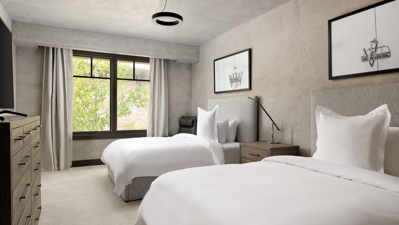 Bedroom with two beds, grey headboards, white sheets, two pictures of ski lifts