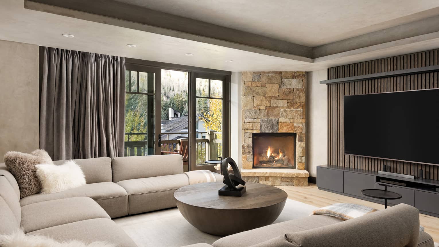 Living room with beige sectional sofa, round wooden coffee table, large TV