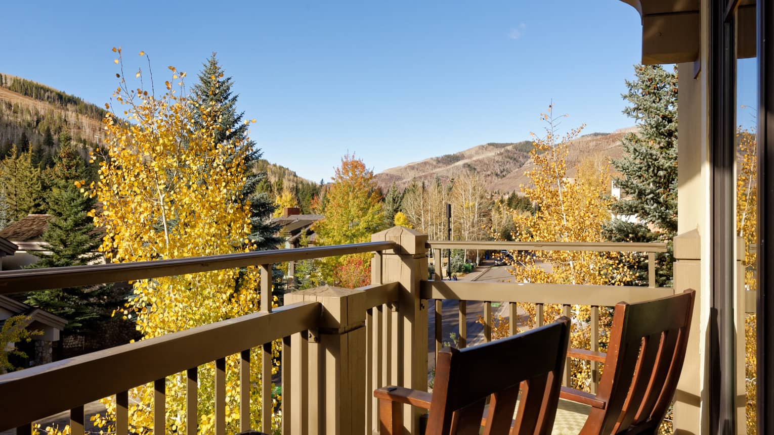Balcony with two wooden chairs looking out to mountains and trees
