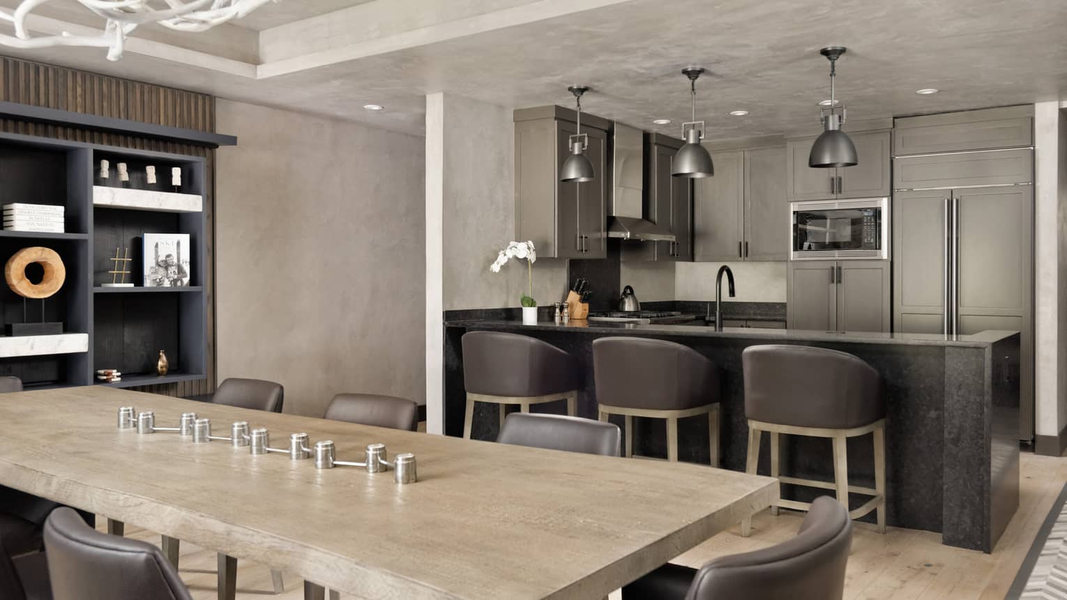 Dining table next to kitchen counter with three leather counter chairs