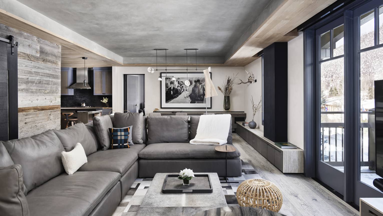 Mountain chic living room with large grey sofa, black framed sliding glass door