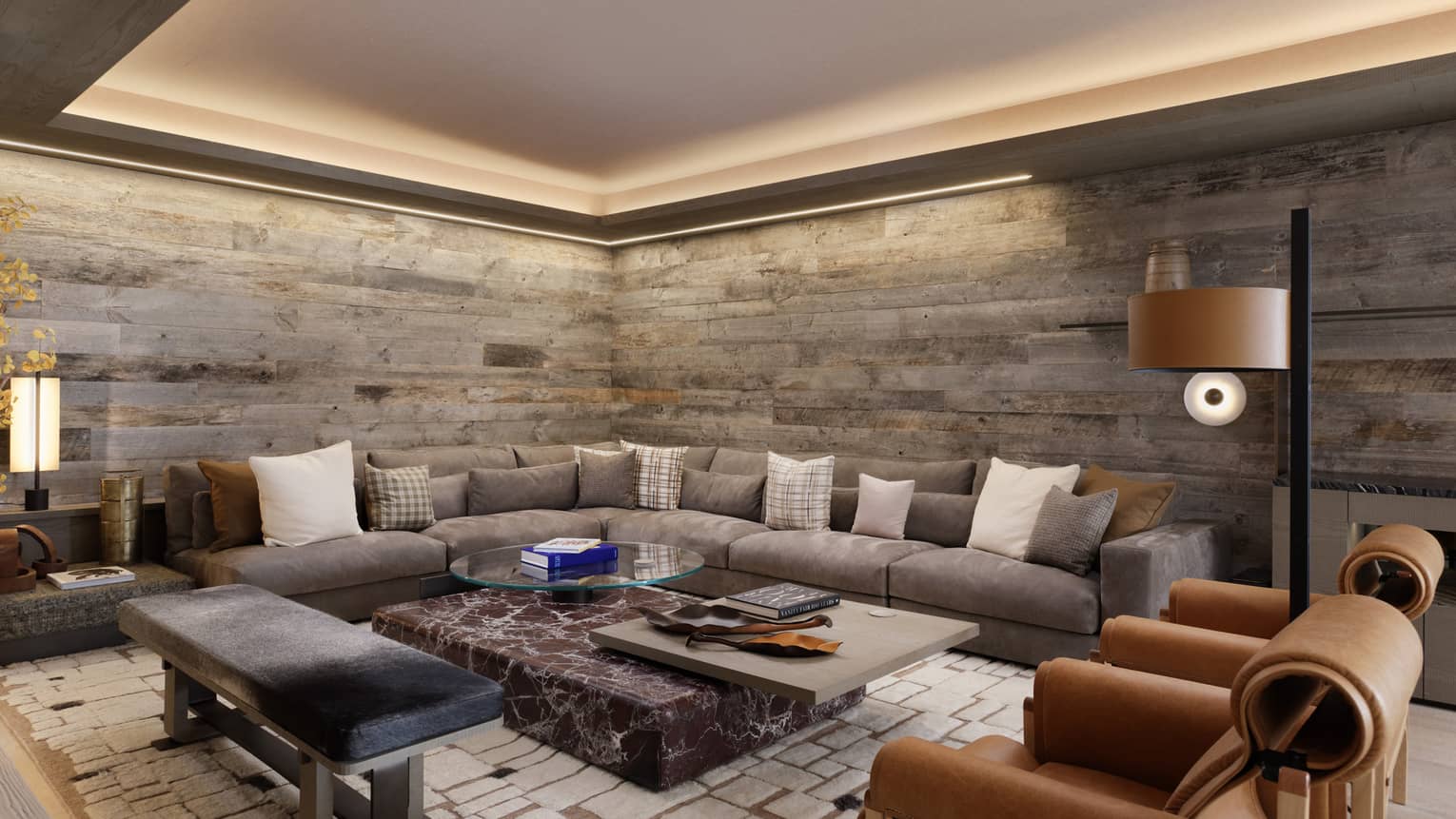 Contemporary living room with stone walls and large grey sectional sofa, two leather arm chairs and bench