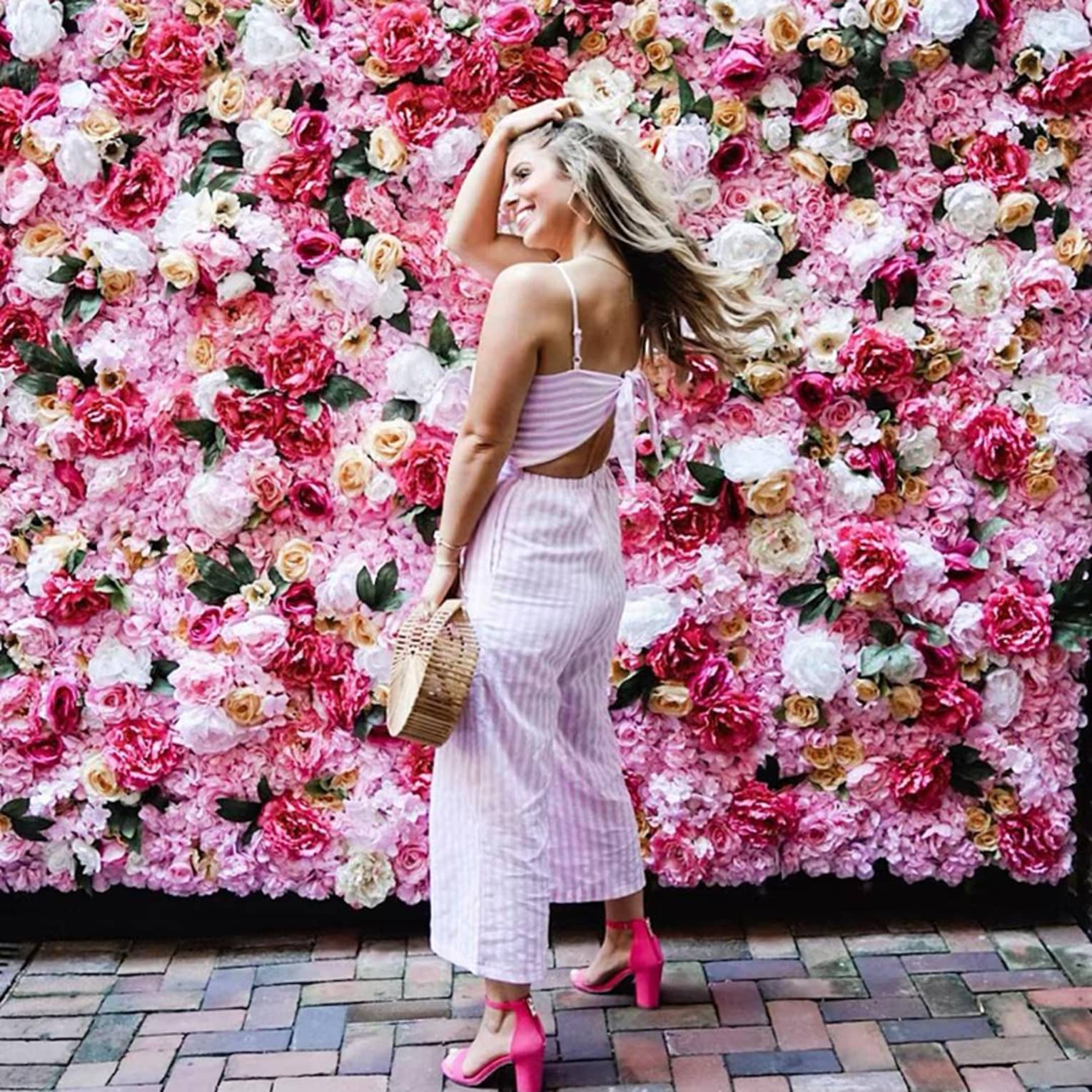 Smiling woman poses in front of wall of roses