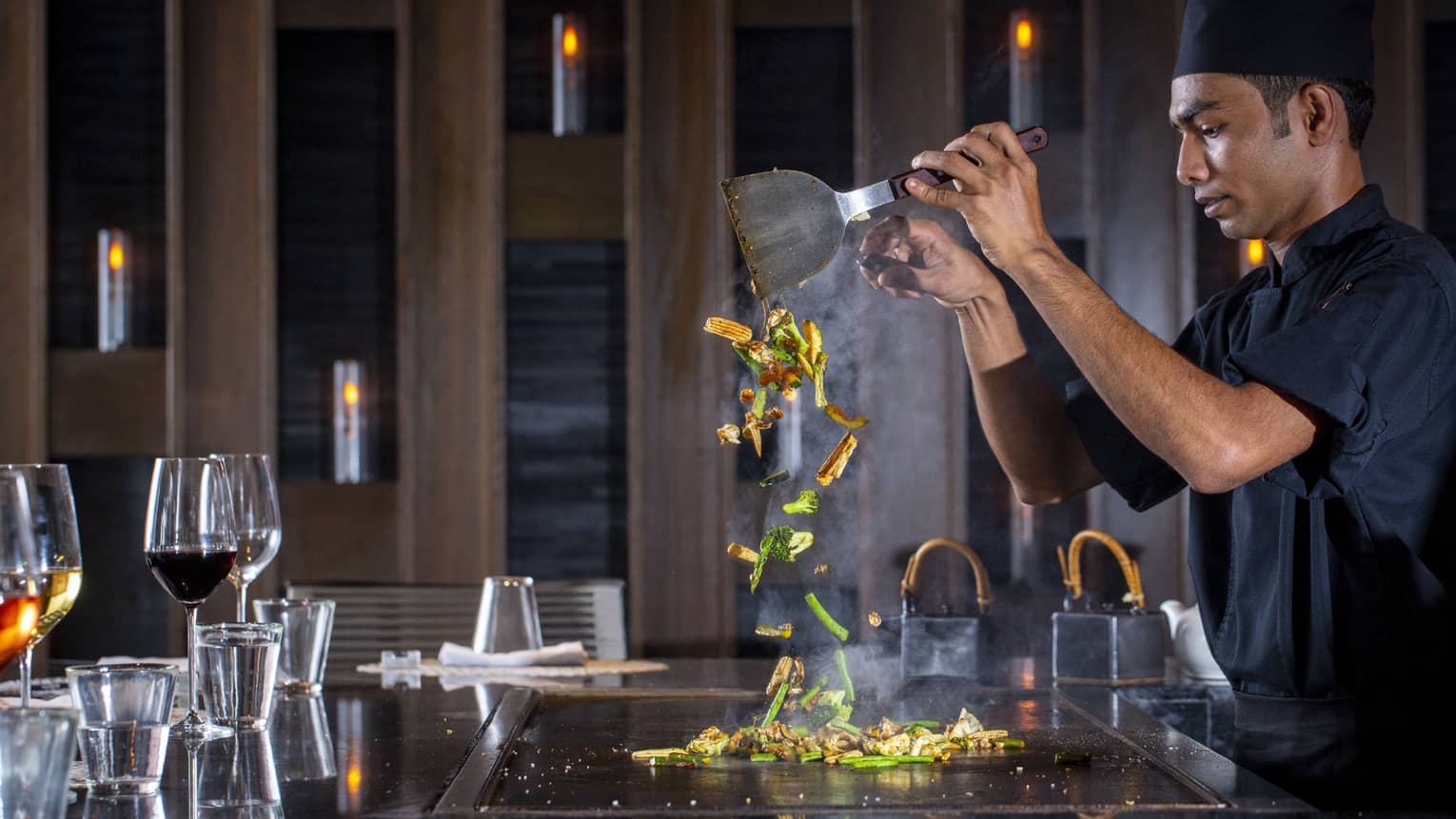 A four seasons dining staff working on a towering dish made of vegetables at the bar