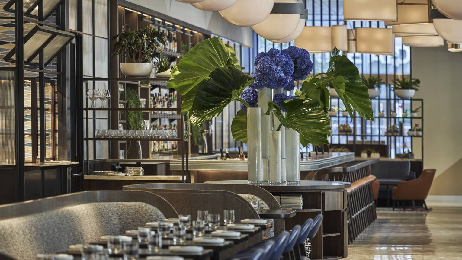 A long table is set with white porcelain plates and clear glasses at Vernick Restaurant in Four Seasons Philadelphia