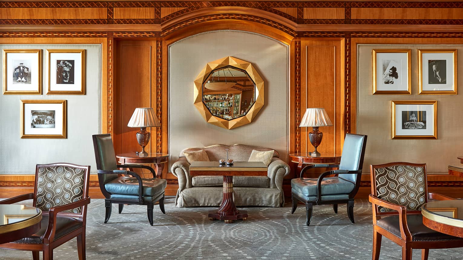 Lounge seating area atop blue carpet against wall with round mirror and artwork