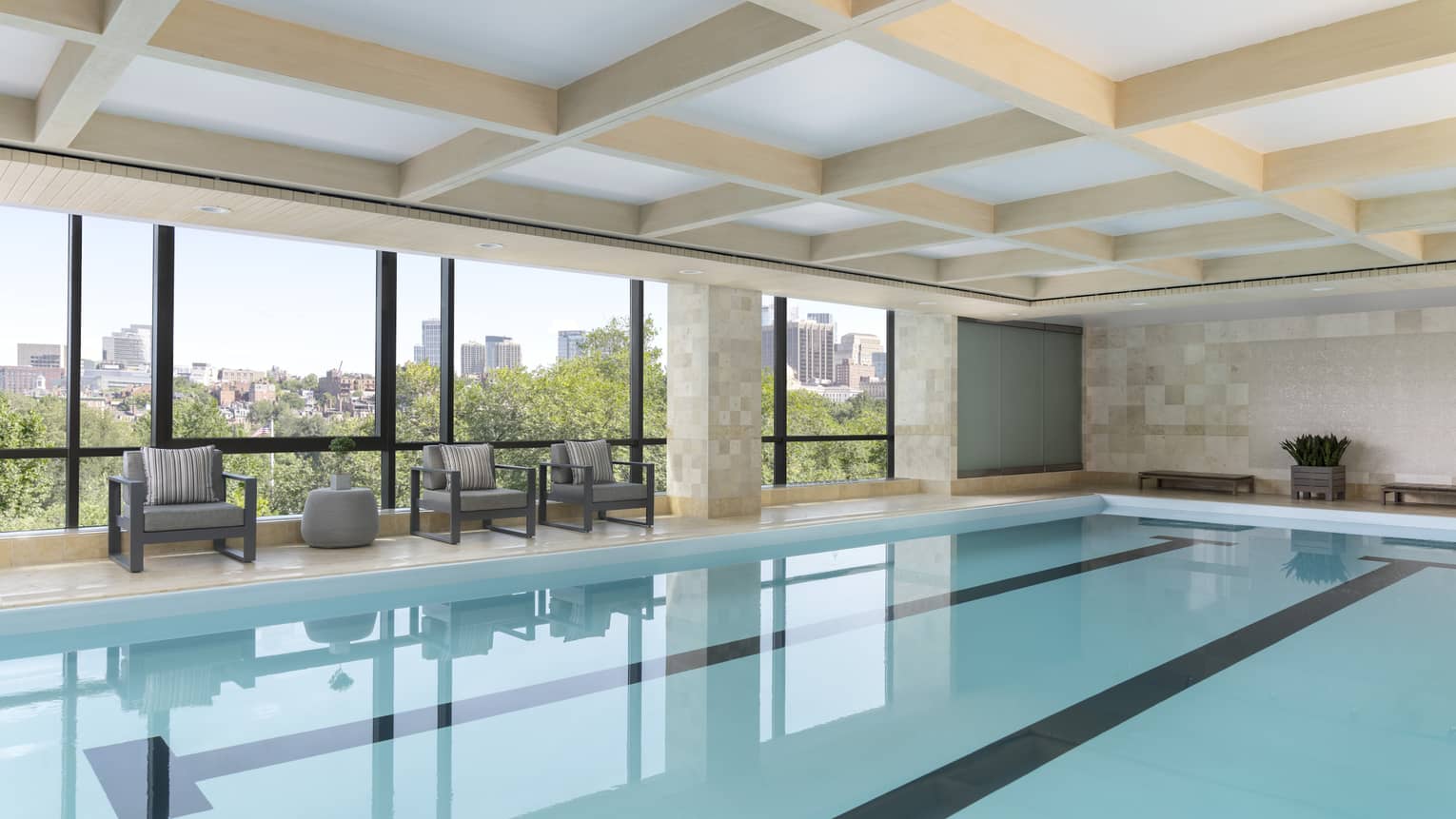 A large indoor pool with large windows and a small sitting areas.