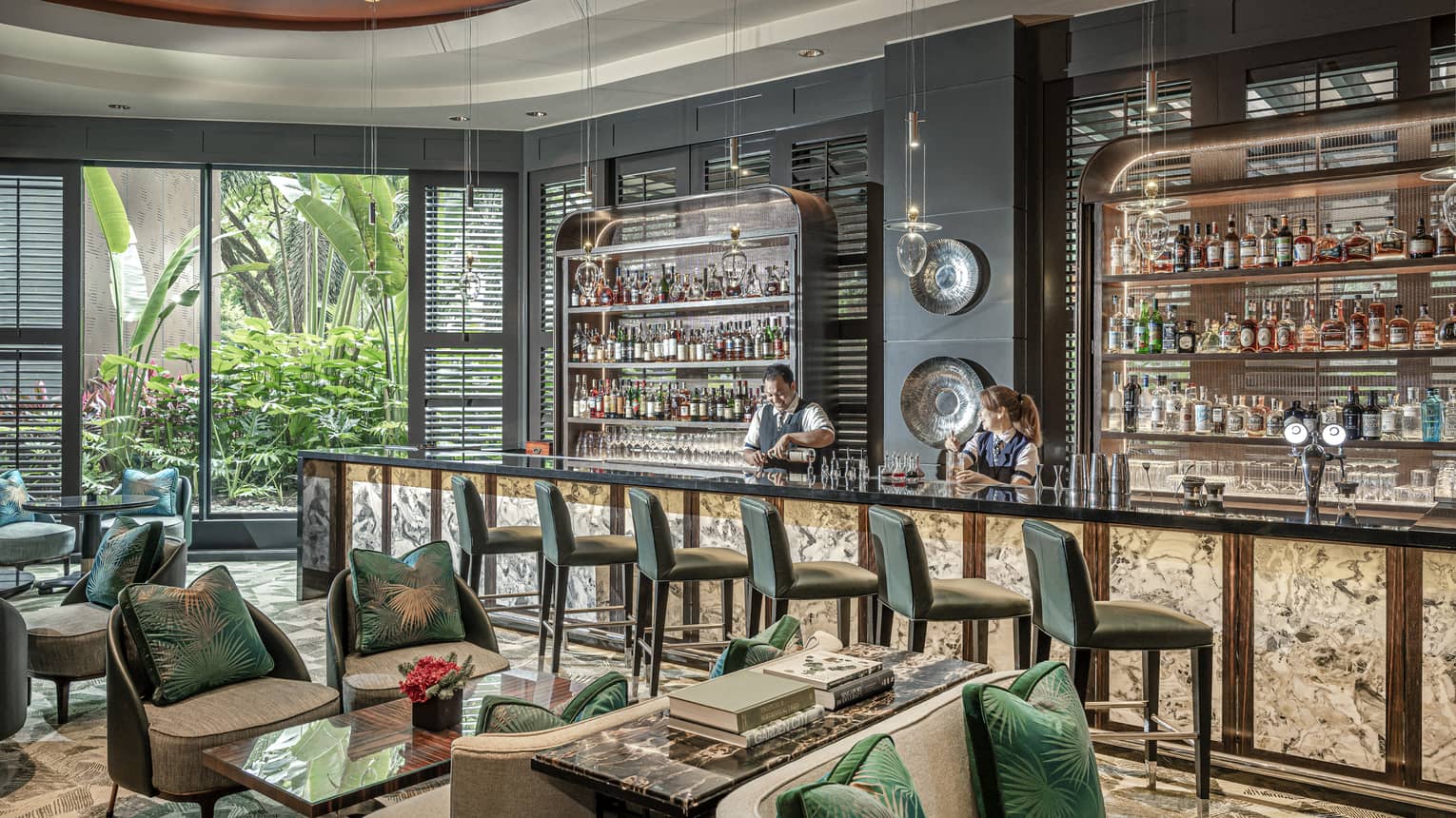 Male and female bartender stand behind counter at light-filled One-Ninety Bar