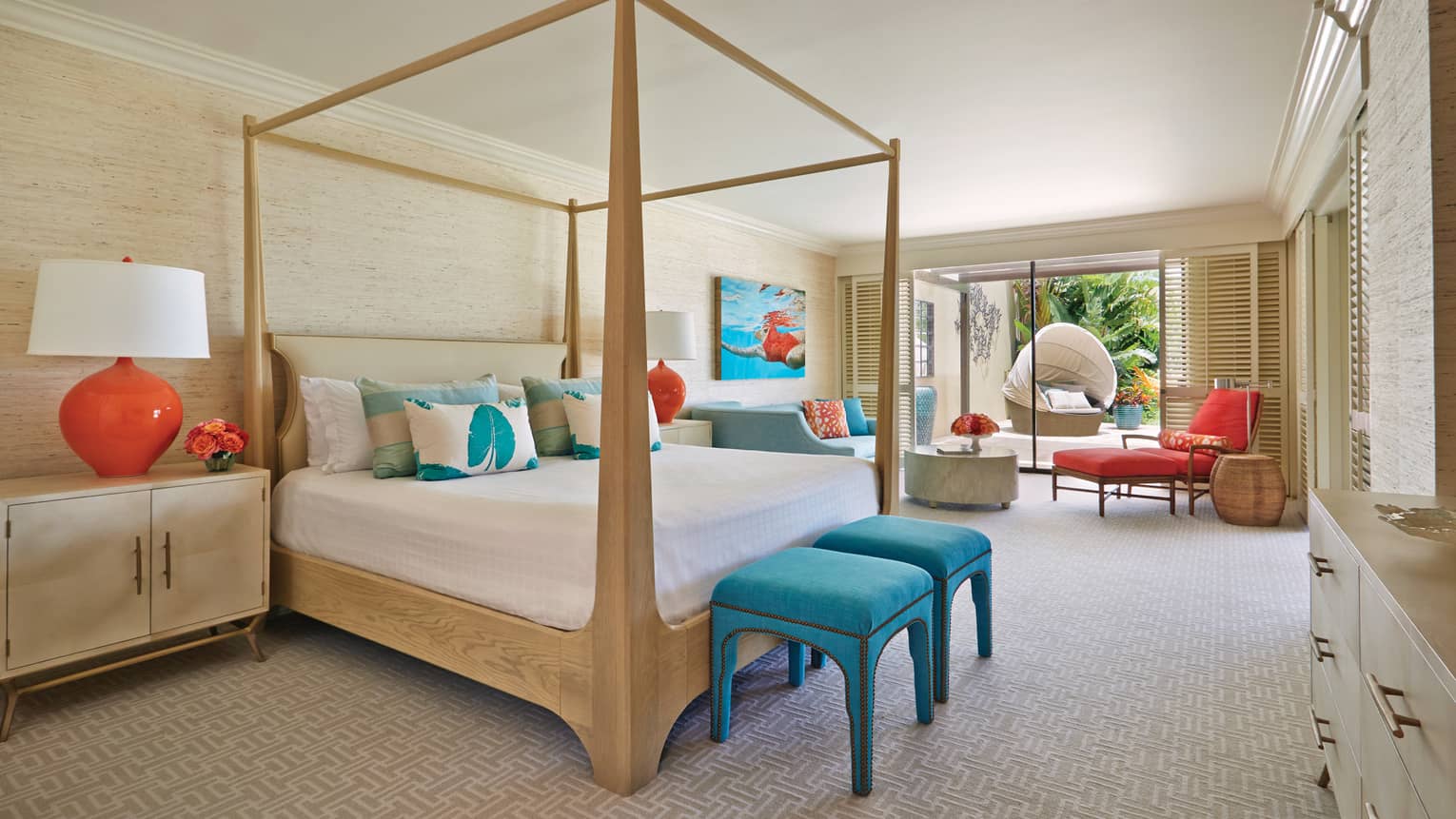 Bright bedroom with canopy bed, colourful accents, lounge area and sliding doors opening to garden patio