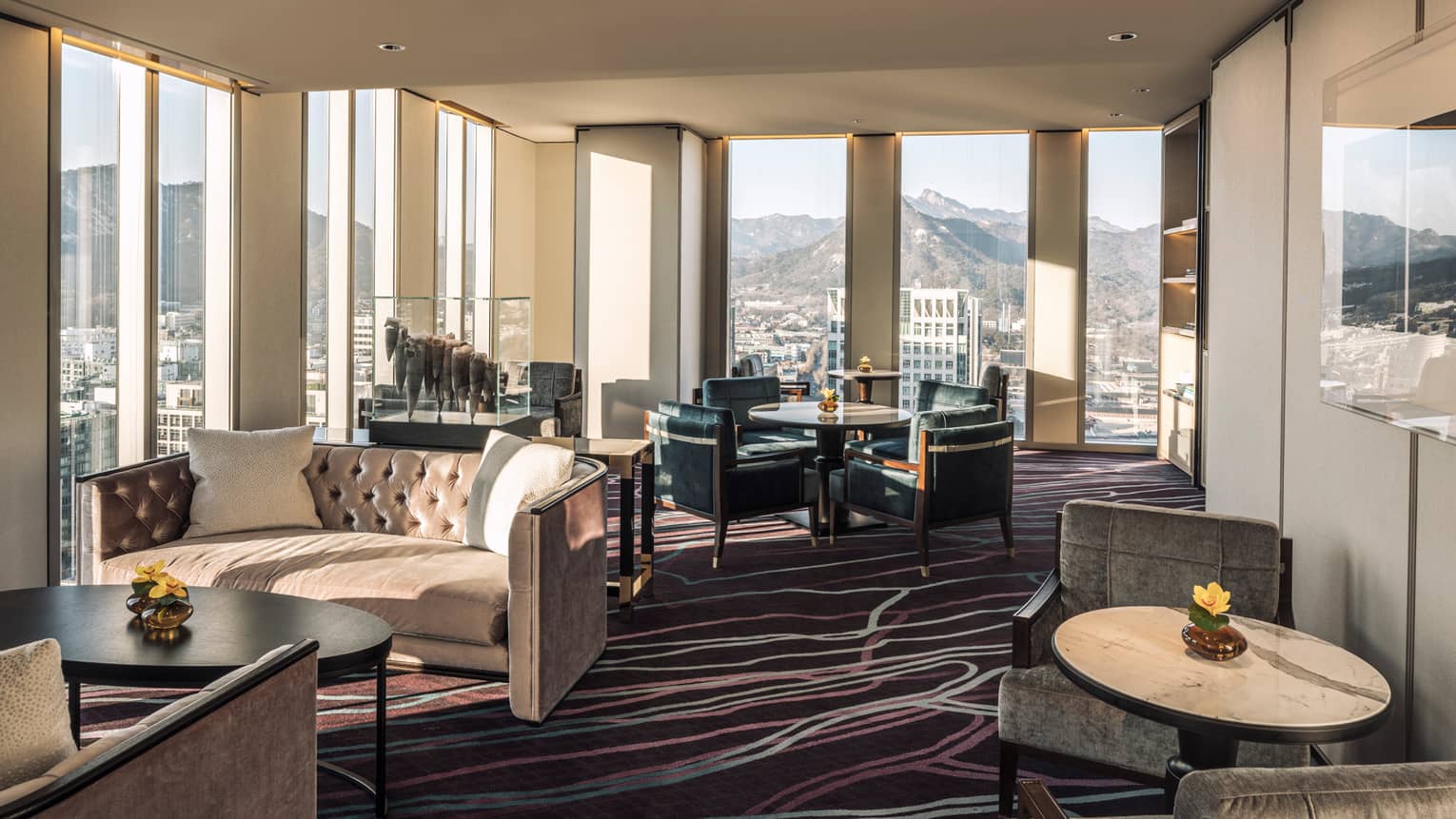 Lounge with tufted velvet sofas, cocktail tables and armchairs, floor-to-ceiling windows