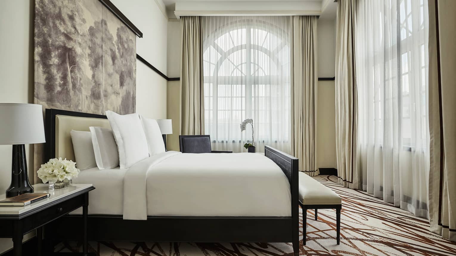 Governor's Suite bedroom, crisp white decor, sunny, arched corner windows with sheer curtains