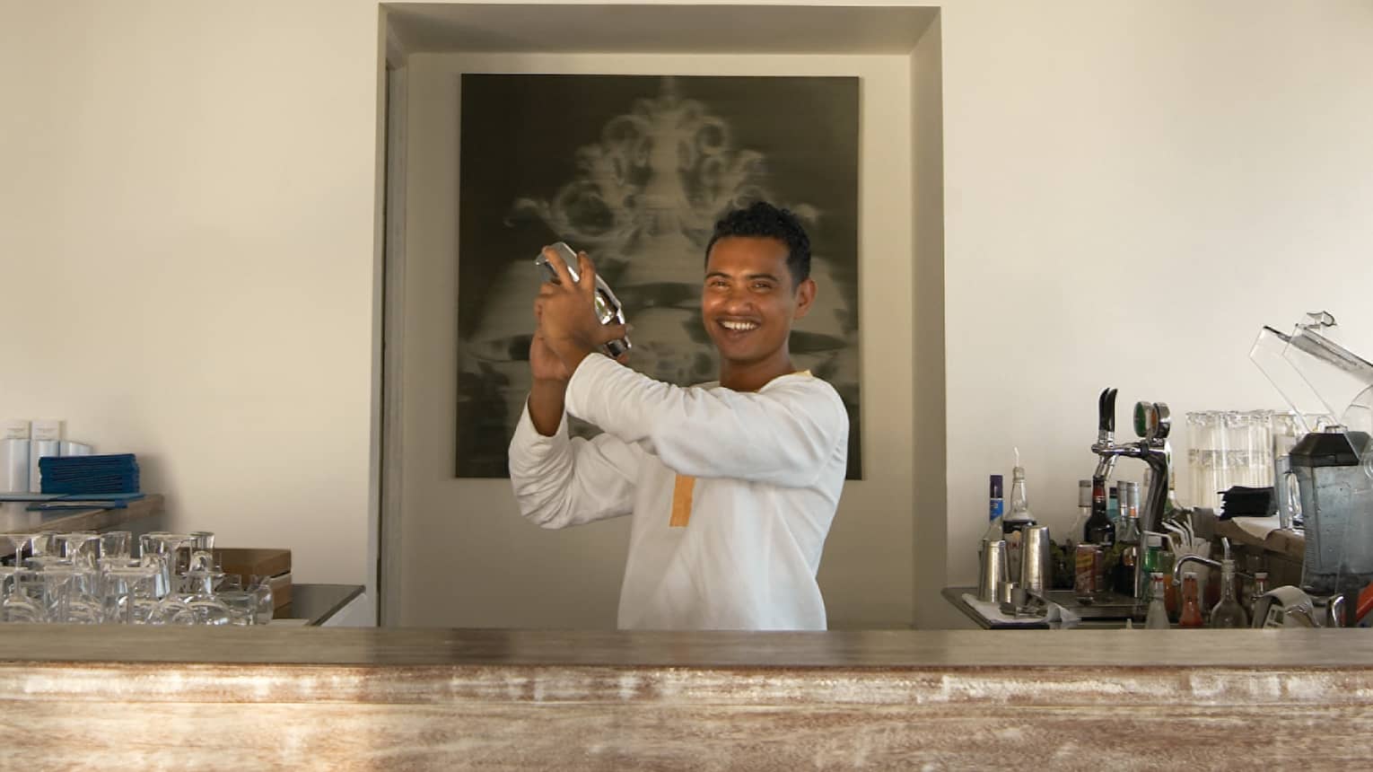 Smiling bartender shaking cocktail behind bar at Seabar lounge