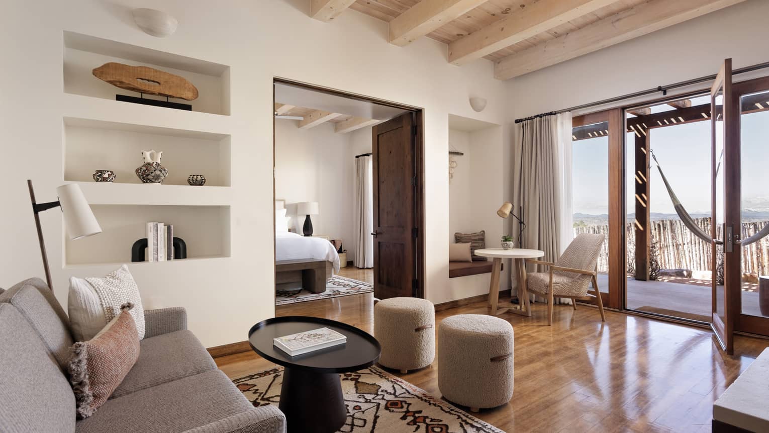 A living room in a suite with a couch and coffee table, and hammock on the patio