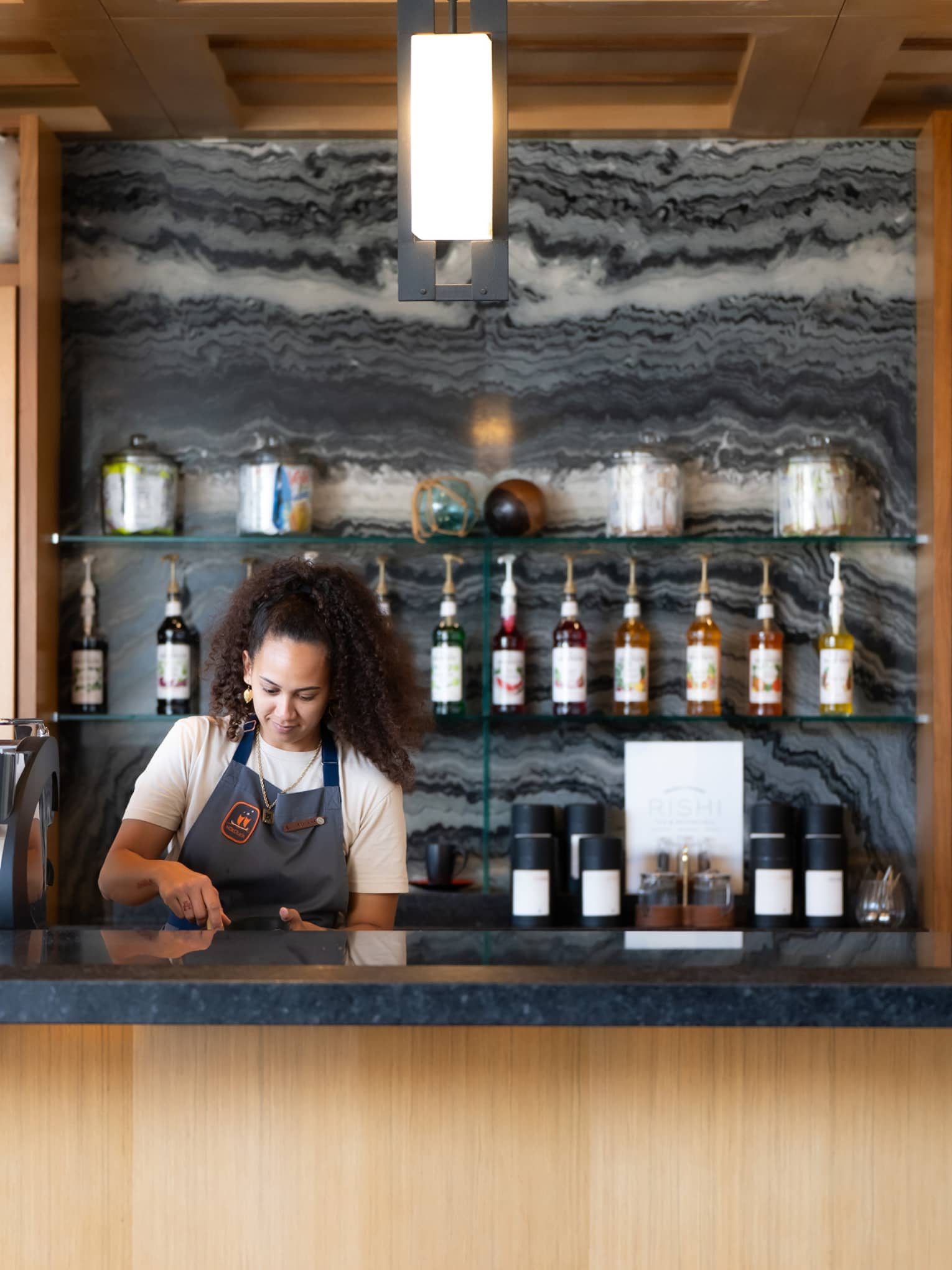 A woman wearing apron works behind a caf� counter
