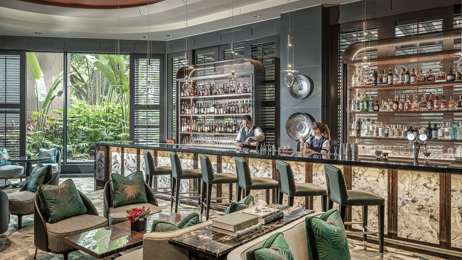 Male and female bartender stand behind counter at light-filled One-Ninety Bar