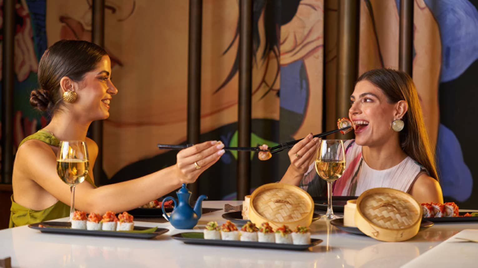Two people enjoy dim sum with chopsticks from small bamboo steamer baskets are restaurant