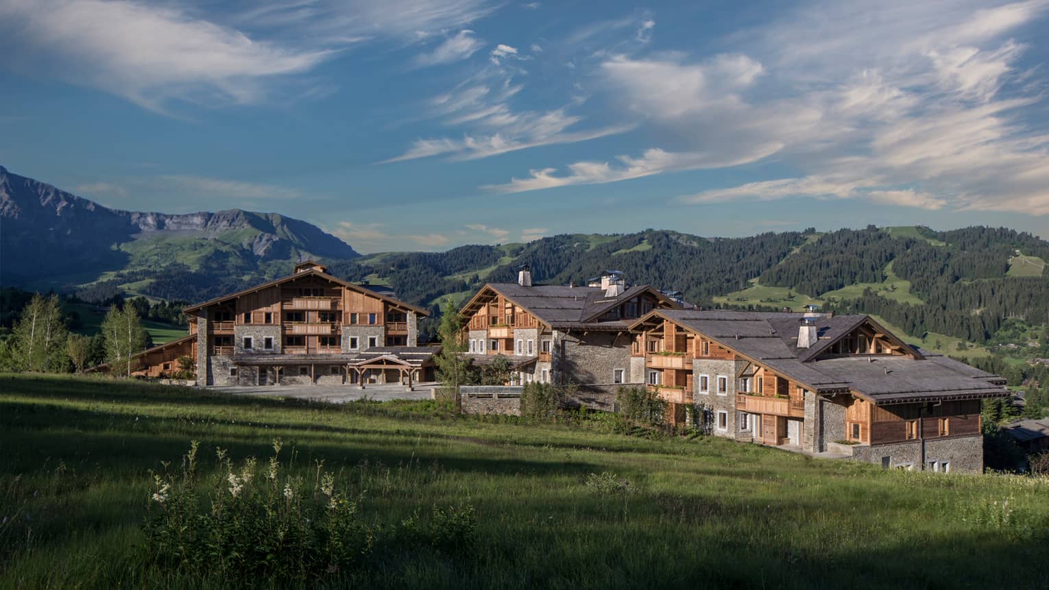 Four Seasons Hotel Mègeve rustic ski resort at edge of meadow, mountains