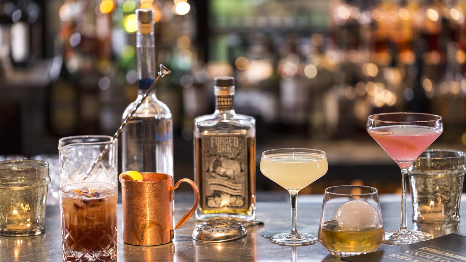 Various cocktails, liquor bottles and shakers on bar