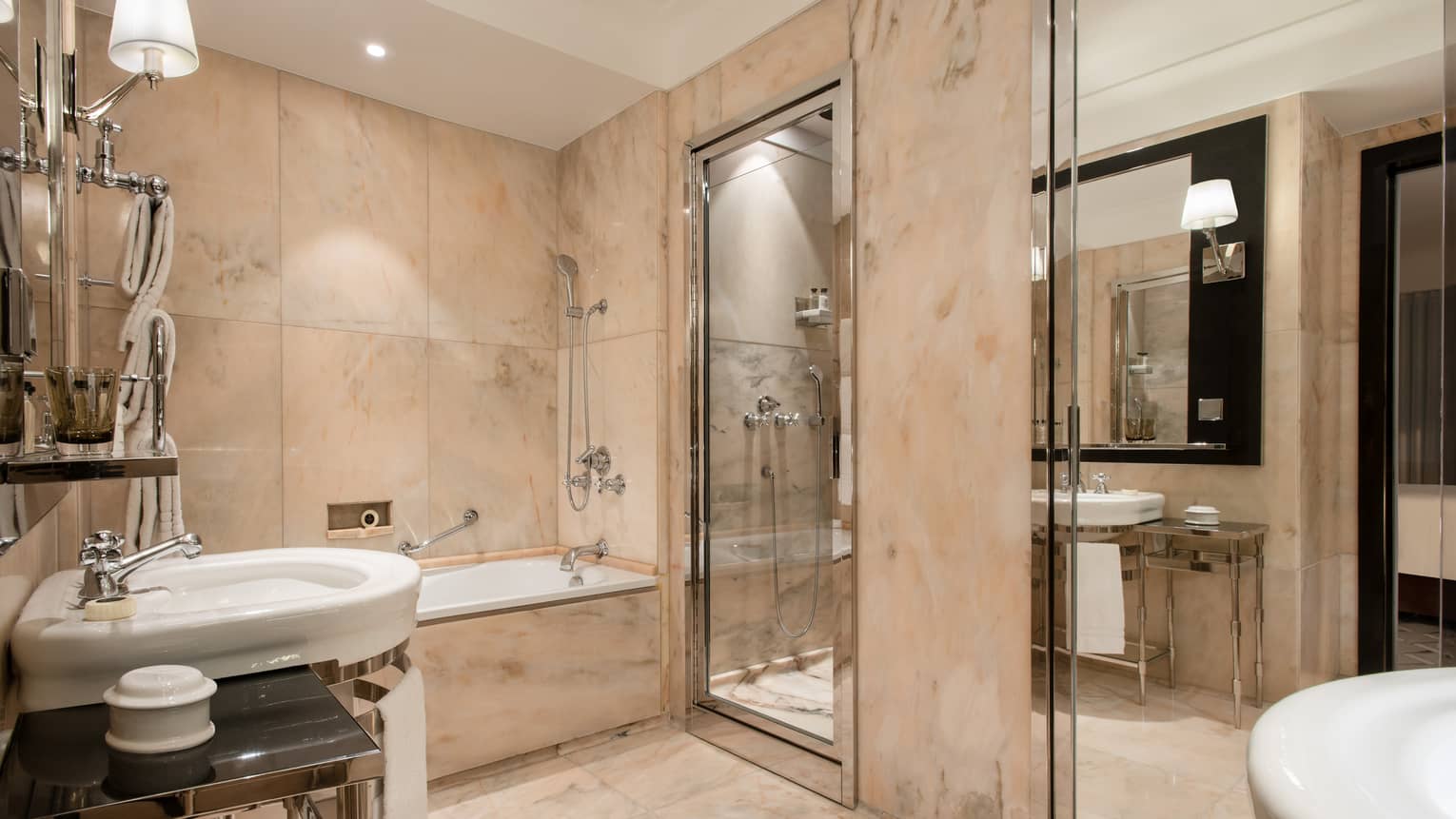 Full beige marble bathroom, free-standing chrome and white sink, bathtub, walk-in shower, tall mirror