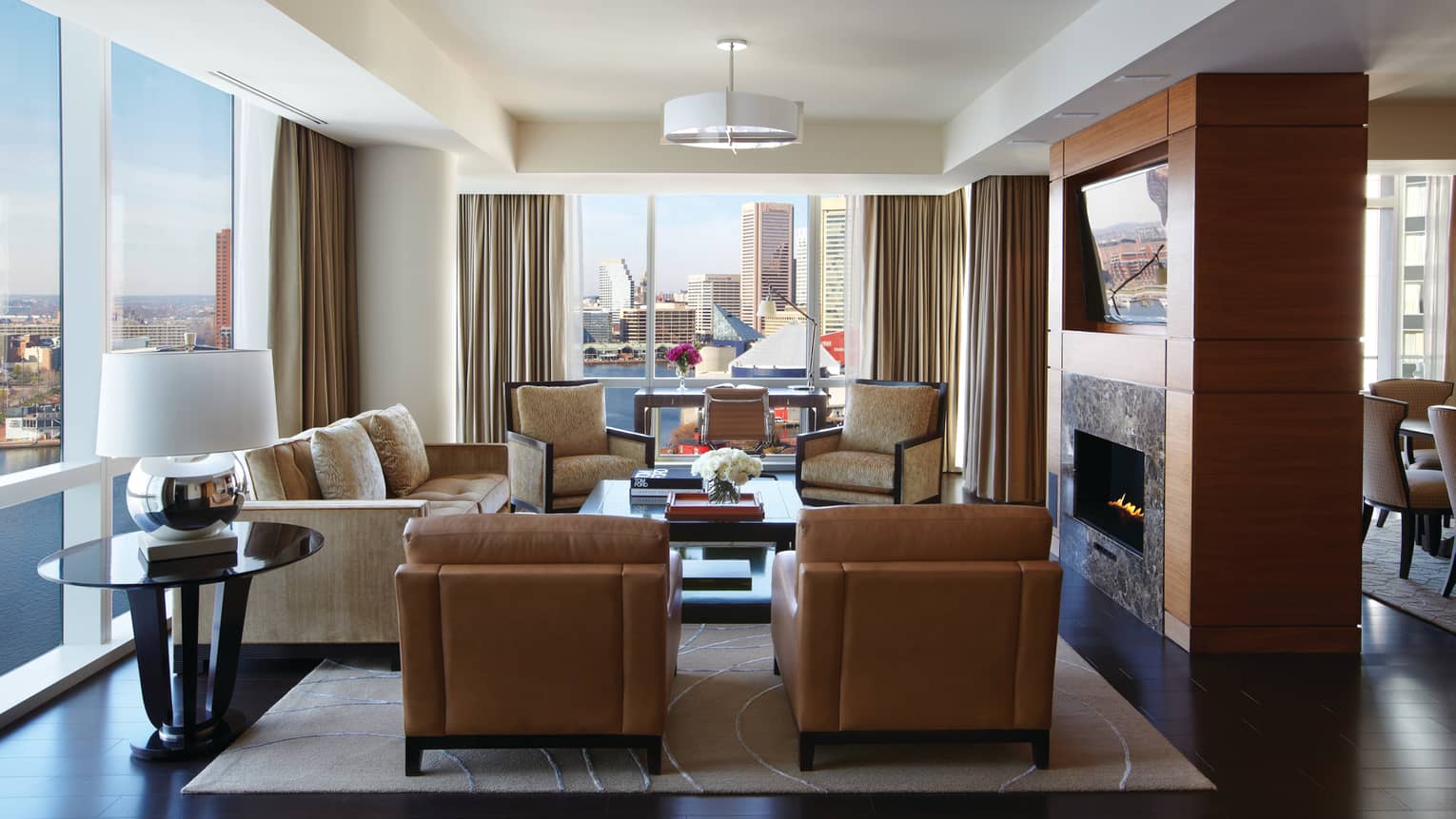Serene Suite brown leather armchairs, sofa, chairs around gas fireplace, corner windows