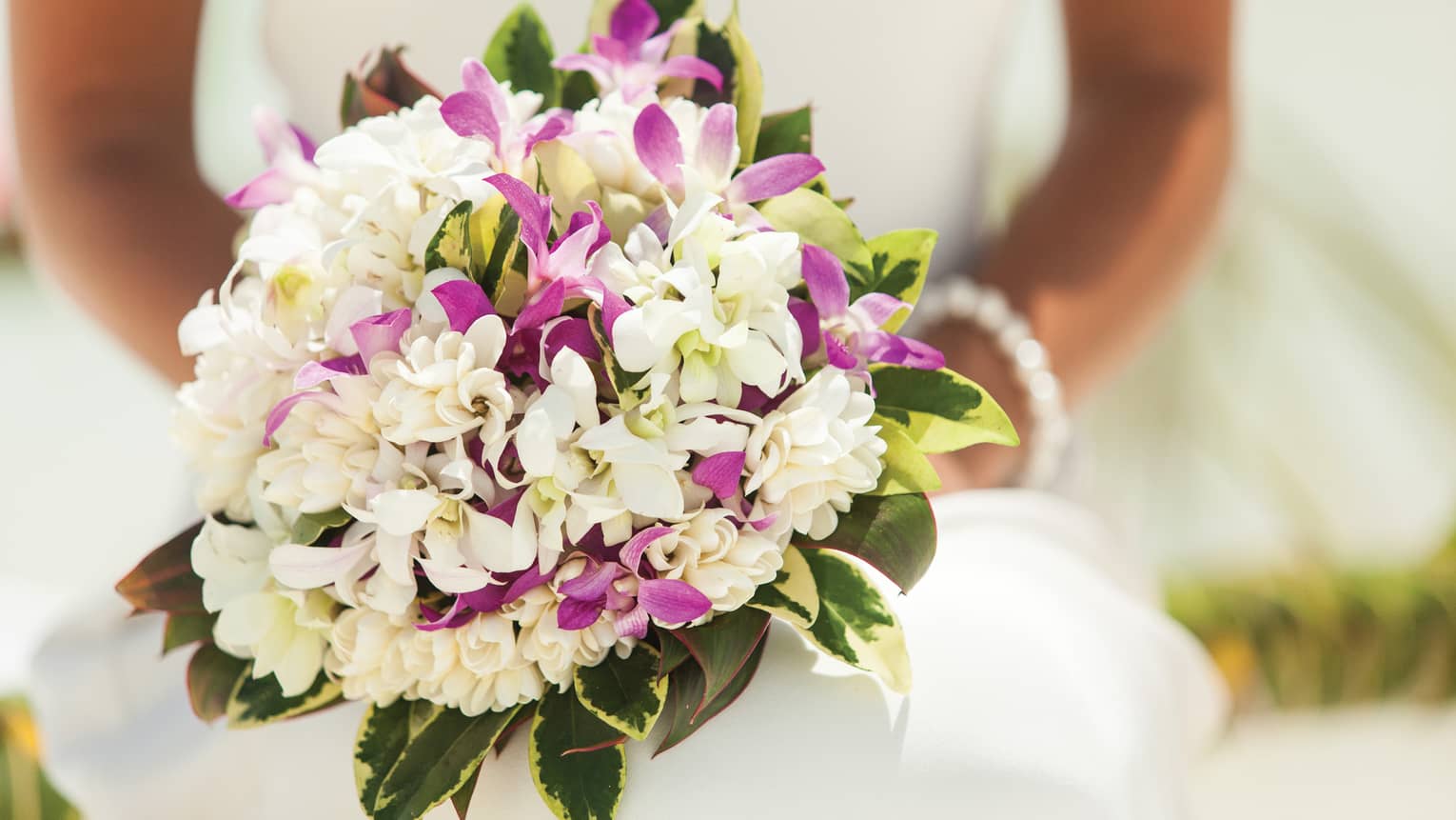 Close-up of bride holding wedding bouquet with purple and white flowers